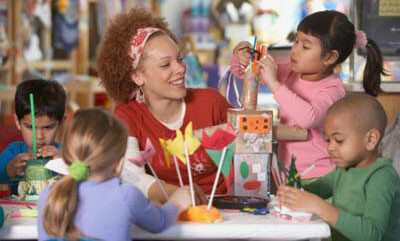 Picture of a teacher with students doing arts &amp; crafts